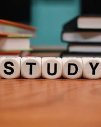 Close-up of study blocks and stacked books on a wooden desk, symbolizing education and learning.